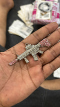 pink and iced out gun pendant